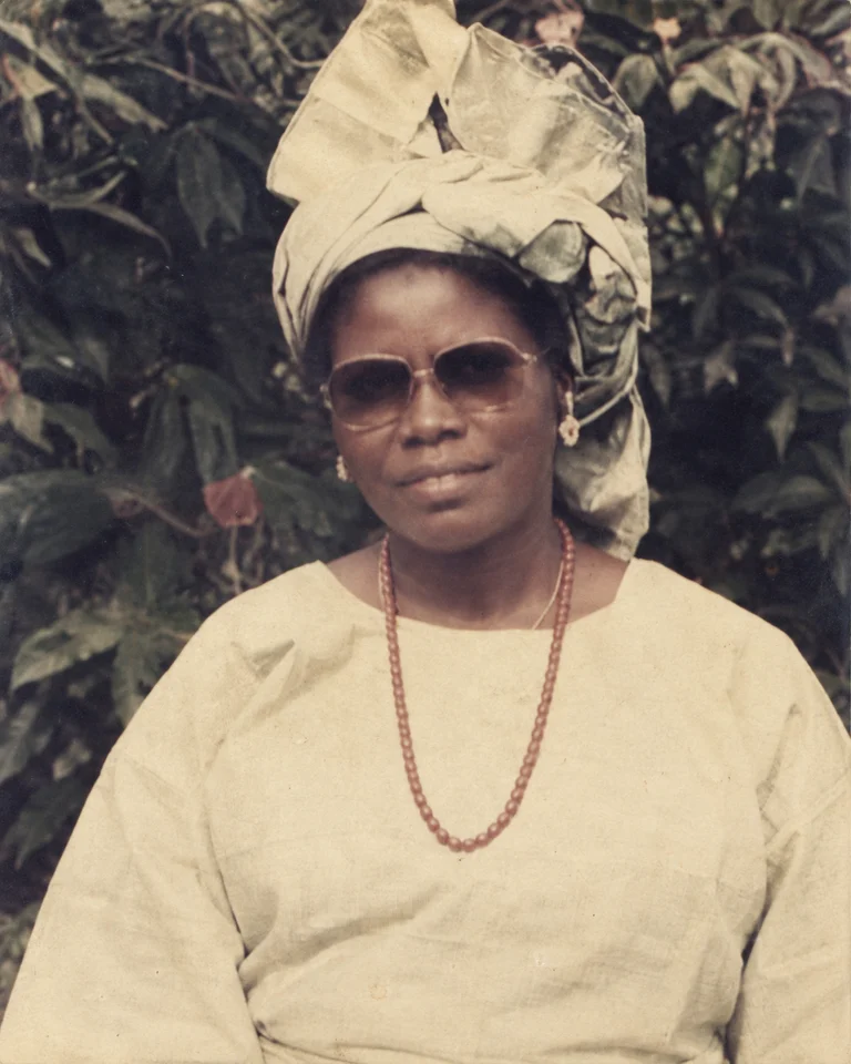 Veronica wearing sunglasses, a pale gele and a necklace
